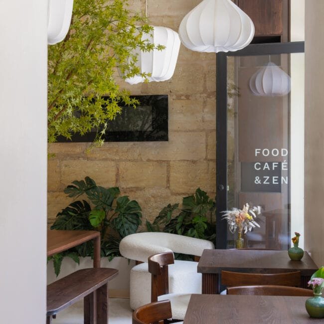 Vue d'ensemble d'un café contemporain à Bordeaux avec mur en pierre et suspensions plissées